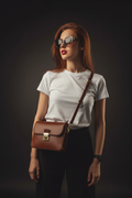 Brown leather crossbody bag - model waist up studio