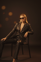 Women's black leather blazer suit seated pose